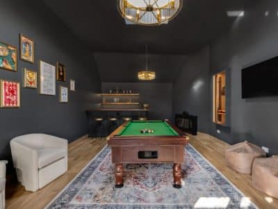 Games room with full-size pool table, built-in bar, wall art, and warm pendant lighting in a luxury holiday let