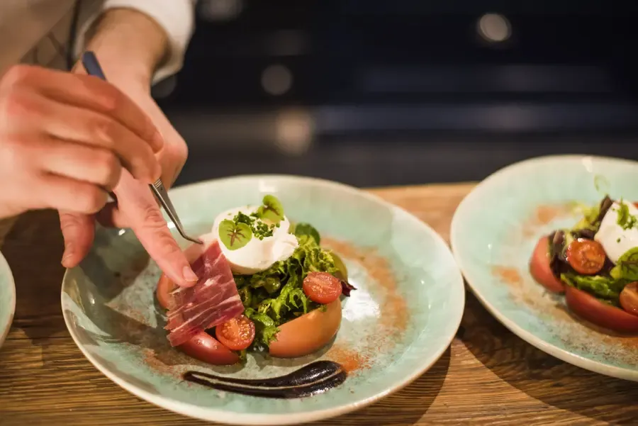 Guest enjoying gourmet plated salad with cured meat and poached egg in luxury chalet dining experience