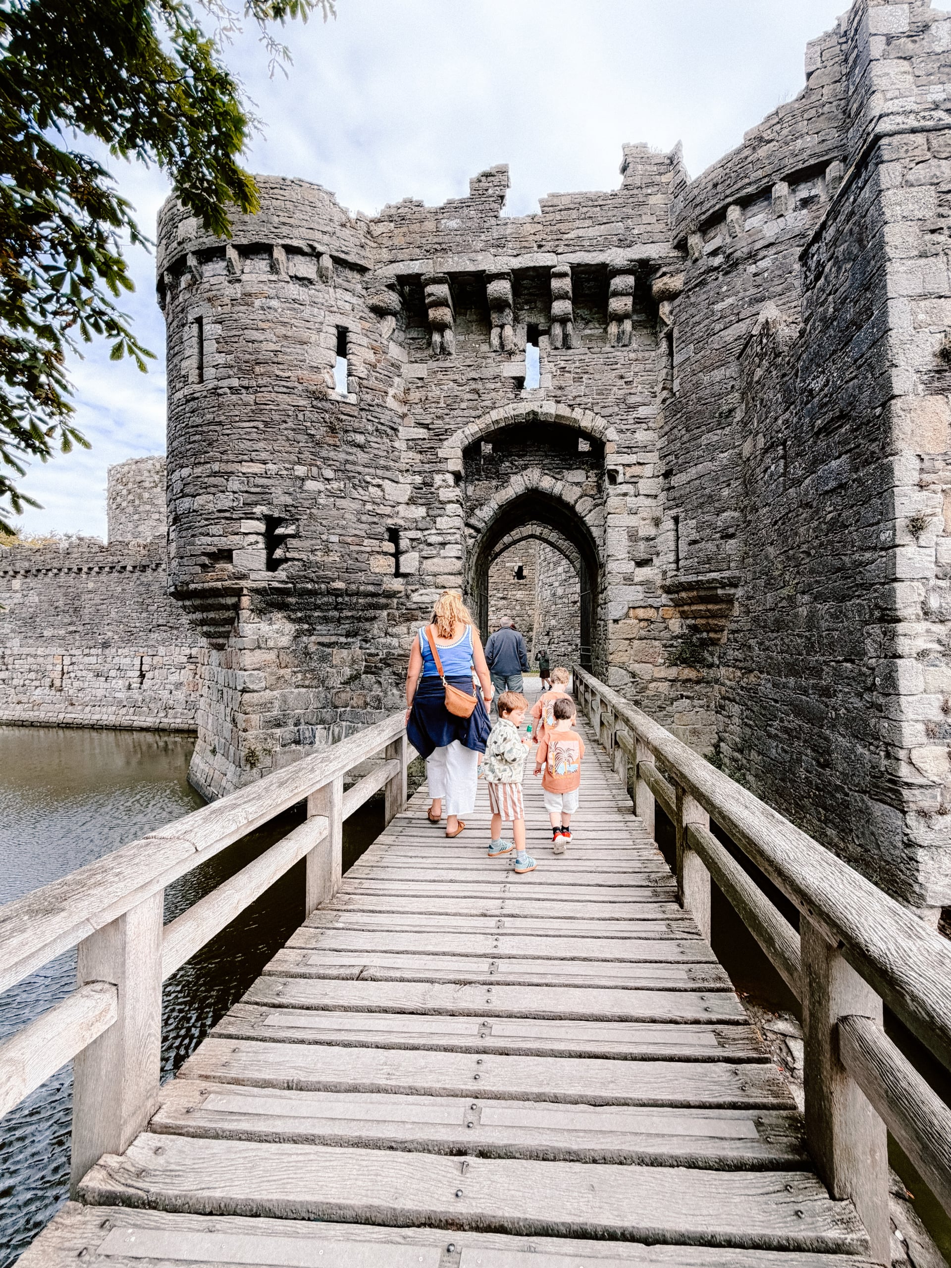 Family crossing the wooden drawbridge into Beaumaris Castle, Anglesey, a perfect day out for guests staying in North Wales