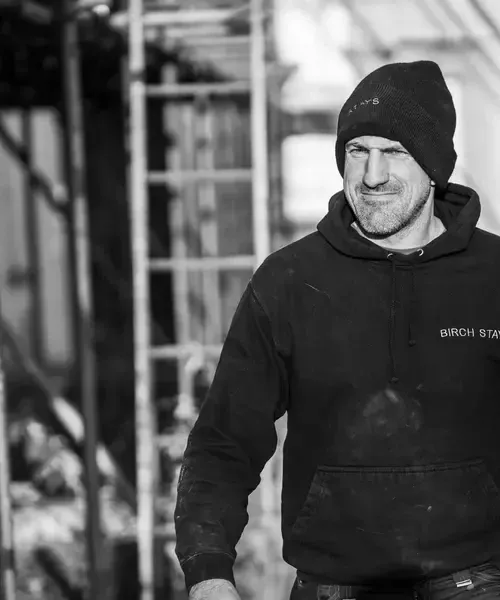 Birch Stays team member in branded hoodie and beanie on a renovation site