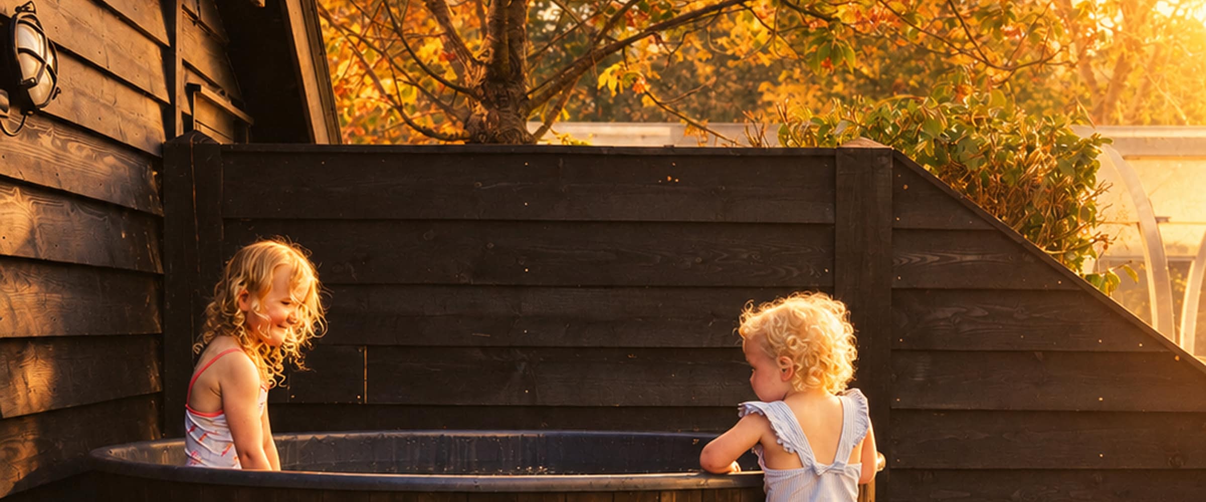 Two young children playing beside an outdoor hot tub at a holiday let, bathed in warm autumn golden-hour light