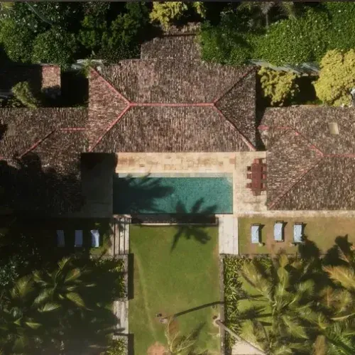 Aerial view of luxury villa with private swimming pool surrounded by tropical gardens and terracotta roof tiles