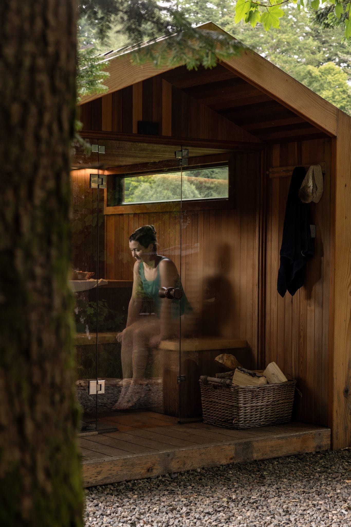 Guest relaxing inside a timber outdoor sauna cabin surrounded by woodland trees at a Scottish holiday cottage
