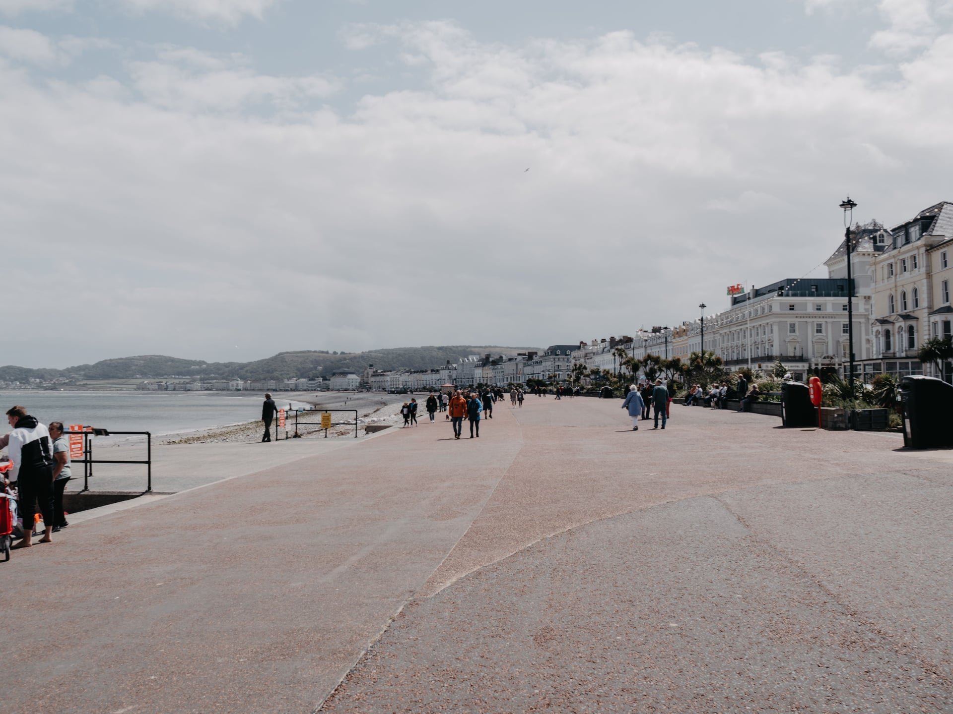 Llandudno promenade on a bright day with Victorian seafront hotels, sandy beach, and the Great Orme headland in the distance