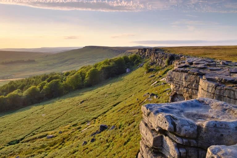Golden evening light over Stanage Edge gritstone escarpment with sweeping Peak District moorland views beyond