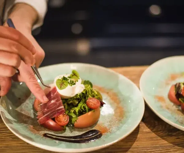 Chef plating gourmet dish with sliced meat and microgreens in luxury holiday let kitchen